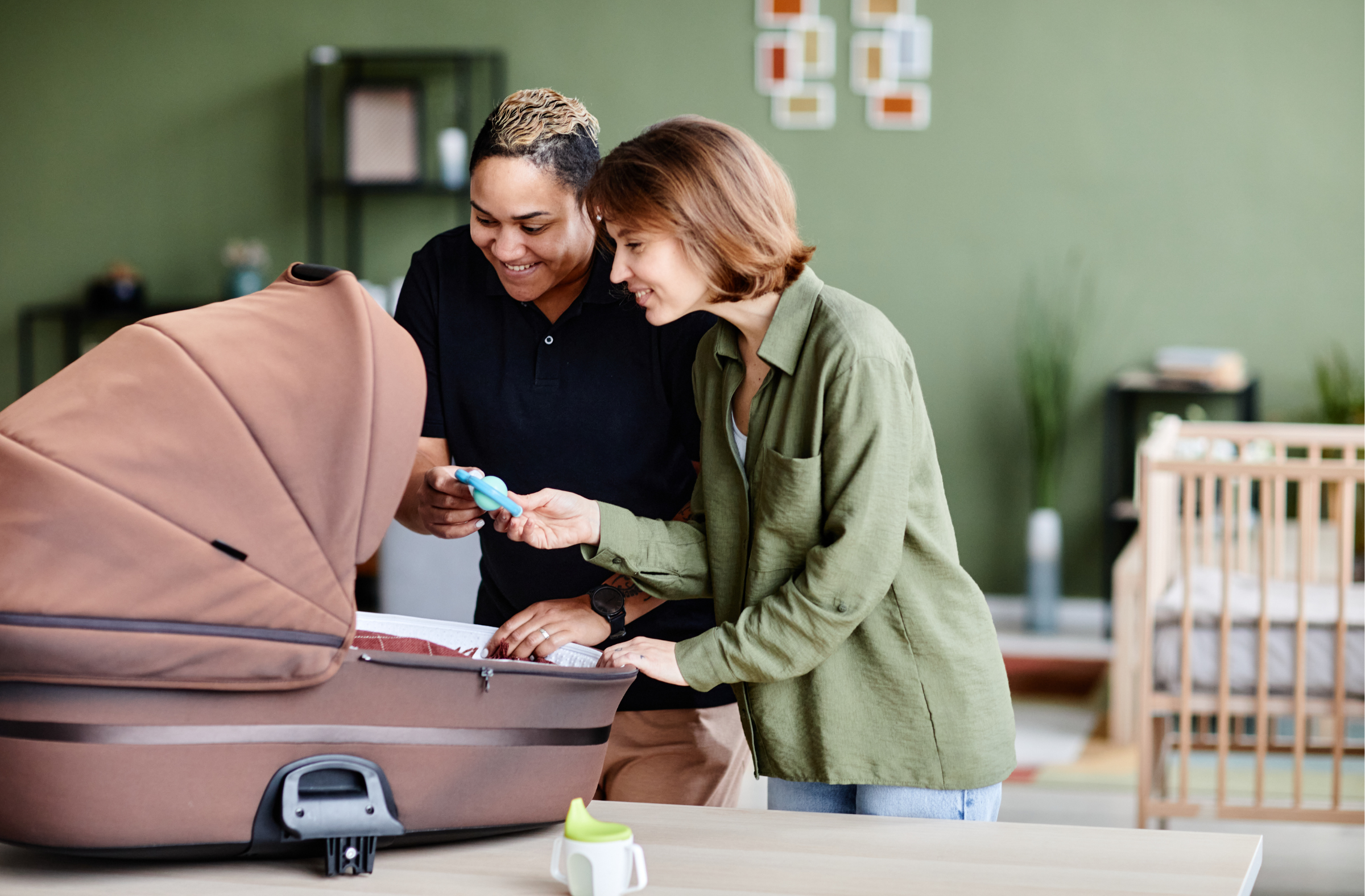Two women standing together at home preparing a baby pram for their newborn